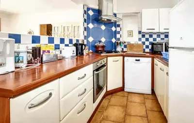 a kitchen with white cabinets and blue and white tiles at Villa ensoleillée & Piscine privée à Aléria in Aléria