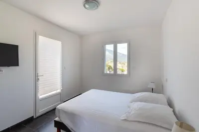 a white bedroom with a bed and a window at Matteo Laricio in Peri