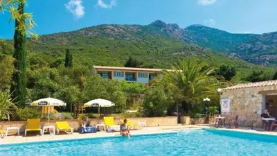a swimming pool with chairs and umbrellas and a house at Appart'Hôtel A Punta in Galeria
