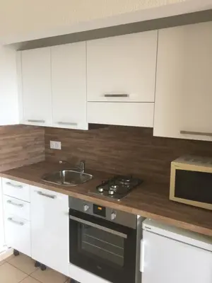 a kitchen with white cabinets and a sink and a stove at Appart'Hôtel A Punta in Galeria