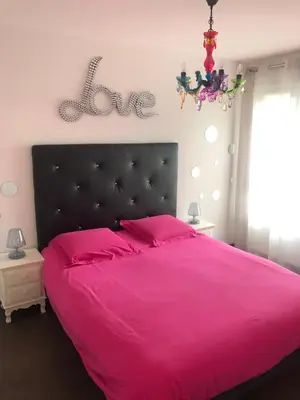 a bedroom with a pink bed and a chandelier at Joli T2 récent 'Le VIVALDI' in Ajaccio