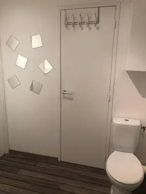 a bathroom with a toilet and a glass door with envelopes at Joli T2 récent 'Le VIVALDI' in Ajaccio