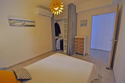 a bedroom with a bed and a closet and a chandelier at Soleil Topaze - 68 m2 - Terrasse - Jardinet - Transats - Vue mer panoramique sur toute la baie in Porticcio
