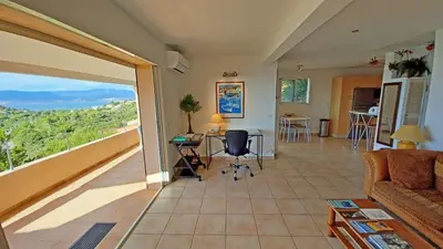 a living room with a view of the ocean at Soleil Topaze - 68 m2 - Terrasse - Jardinet - Transats - Vue mer panoramique sur toute la baie in Porticcio