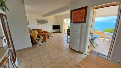 a living room with a couch and a table at Soleil Topaze - 68 m2 - Terrasse - Jardinet - Transats - Vue mer panoramique sur toute la baie in Porticcio