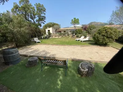 a park bench sitting in the middle of a yard at Villa Poggio Rosso - Pool-House & Piscine chauffée in Sainte-Lucie de Porto-Vecchio