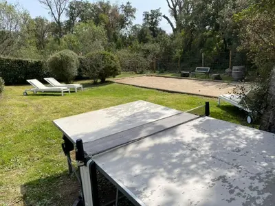 a ping pong table in a yard with two benches at Villa Poggio Rosso - Pool-House & Piscine chauffée in Sainte-Lucie de Porto-Vecchio