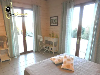 a bedroom with a bed and a desk and windows at Dormir à Porto Vecchio (Trinité) in Porto-Vecchio
