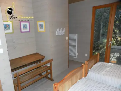 a bedroom with a bed and a bench and a window at Dormir à Porto Vecchio (Trinité) in Porto-Vecchio