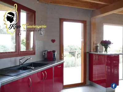 a kitchen with red cabinets and a sink and windows at Dormir à Porto Vecchio (Trinité) in Porto-Vecchio