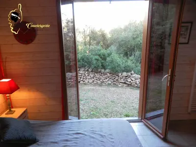 a bedroom with a sliding glass door to a yard at Dormir à Porto Vecchio (Trinité) in Porto-Vecchio