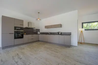 a kitchen with white cabinets and a wooden floor at Maison Del Onda in Lecci