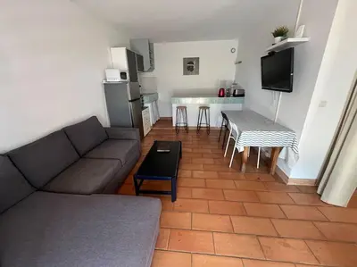 a living room with a couch and a table and a kitchen at Rez de villa bordure Ajaccio in Ajaccio