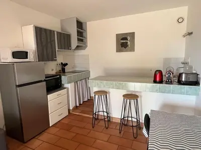 a kitchen with a refrigerator and two bar stools at Rez de villa bordure Ajaccio in Ajaccio