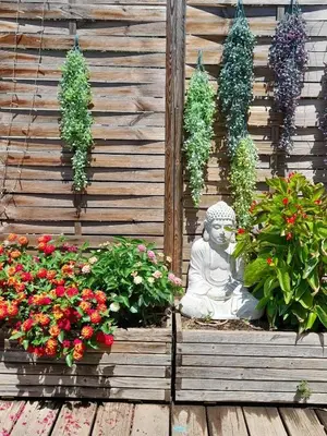 a statue in front of a wooden wall with flowers at casa turchina chambre avec piscine privée in Porto-Vecchio