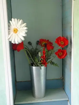 a metal vase with red and white flowers in it at casa turchina chambre avec piscine privée in Porto-Vecchio