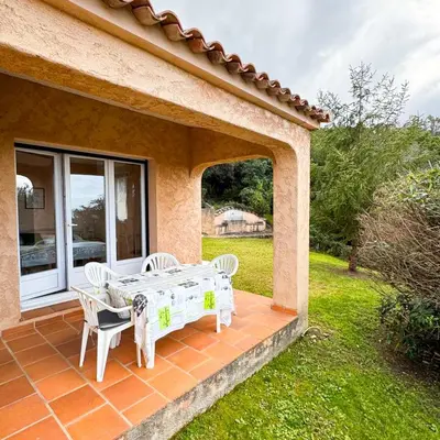 a patio with a table and two chairs on a house at Domaine Mare e Monti - T1 Les Palmiers vue mer in Albitreccia