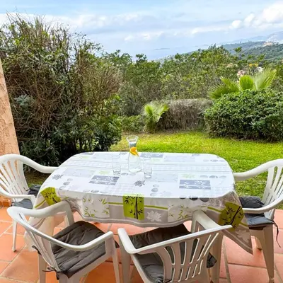 a table with a glass of wine and two chairs at Domaine Mare e Monti - T1 Les Palmiers vue mer in Albitreccia