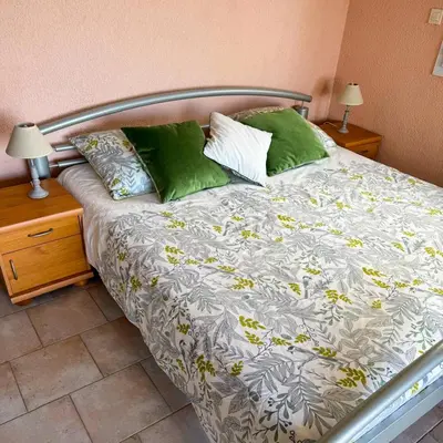 a bed with green pillows on it in a bedroom at Domaine Mare e Monti - T1 Les Palmiers vue mer in Albitreccia