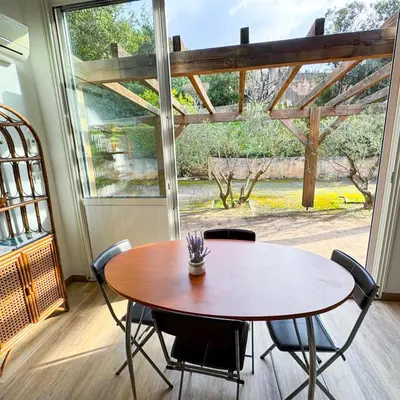 a table and chairs in a room with a large window at Domaine Mare e Monti - T2 Les Oliviers vue mer in Albitreccia
