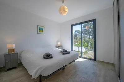 a white bedroom with a bed and a large window at Villa calme luxueuse et proche plage saint-cyprien in Lecci