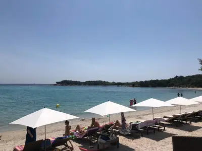 a group of people sitting on a beach with umbrellas at Villa calme luxueuse et proche plage saint-cyprien in Lecci