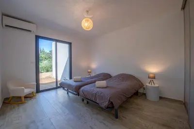 a bedroom with a bed and a large window at Villa calme luxueuse et proche plage saint-cyprien in Lecci