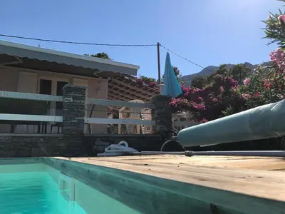 a house with a swimming pool and an umbrella at CHAMBRE HOTES CARPE DIEM in Santa-Maria-Poggio