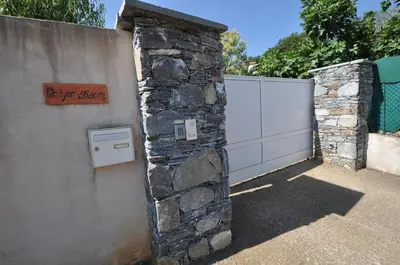 a stone wall with a sign on it next to a fence at CHAMBRE HOTES CARPE DIEM in Santa-Maria-Poggio