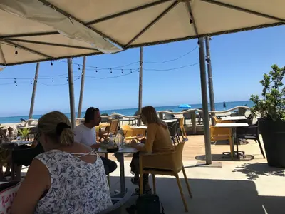 a group of people sitting at tables under umbrellas at CHAMBRE HOTES CARPE DIEM in Santa-Maria-Poggio