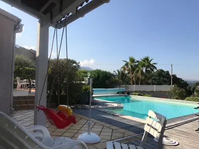 a porch with a swing and a swimming pool at CHAMBRE HOTES CARPE DIEM in Santa-Maria-Poggio