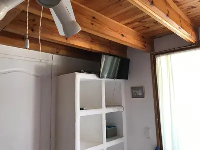 a room with a wooden ceiling with a television on a shelf at CHAMBRE HOTES CARPE DIEM in Santa-Maria-Poggio