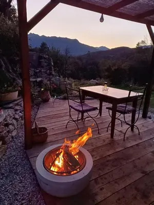a fire pit on a wooden deck with a table at A Chjusella di E Sertine in Tralonca