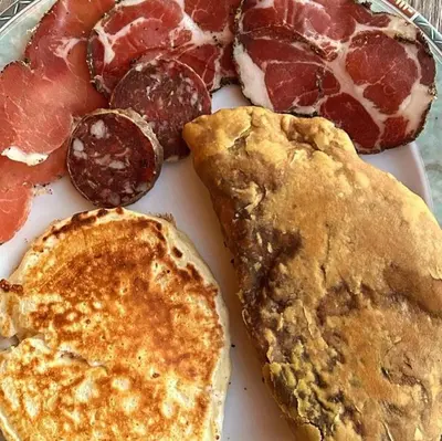 a plate of breakfast food with pancakes and meats at A Chjusella di E Sertine in Tralonca