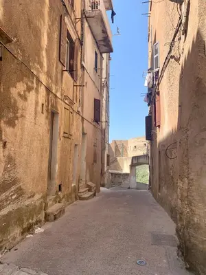 an alley in an old building with a bridge in the background at CASA CITADELLA Bonifacio in Bonifacio
