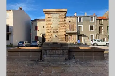 a stone fountain in a parking lot with buildings at FUNTANA NOVA in Piana