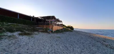 a beach with a building and the ocean at Maison U nidu à 500m de la mer in Cervione