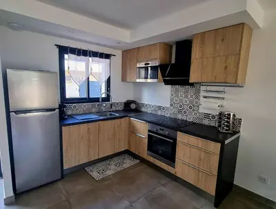 a kitchen with wooden cabinets and a stainless steel refrigerator at Maison U nidu à 500m de la mer in Cervione
