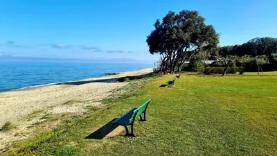 a park bench sitting on the side of a beach at Maison U nidu à 500m de la mer in Cervione