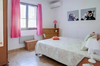 a bedroom with a bed and a window with pink curtains at Villa Bossangoa in Cervione