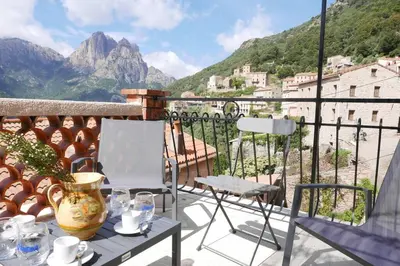 a table and chairs on a balcony with mountains at I MONTI SIGNORI in Porto Ota
