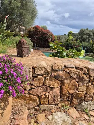 a stone retaining wall with flowers in a yard at Bel appartement dans hameau calme in Bonifacio