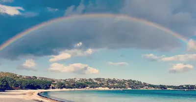 a rainbow over the beach and the water at Bel appartement dans hameau calme in Bonifacio