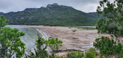 a view of a beach with a mountain in the background at Bel appartement dans hameau calme in Bonifacio