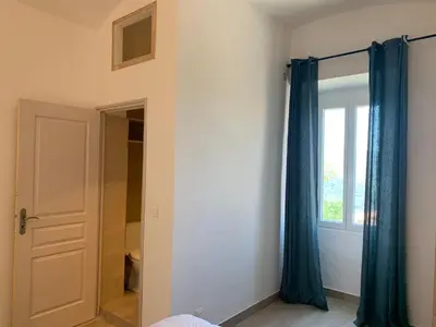 a bedroom with blue curtains and a window at Casa Lisà in Sartène