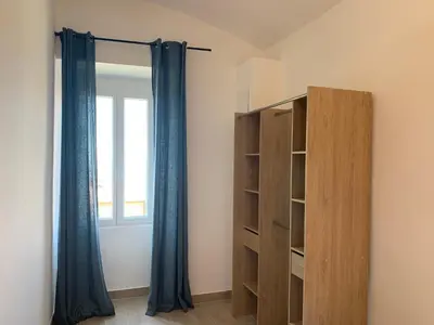 a room with a closet and a window with blue curtains at Casa Lisà in Sartène