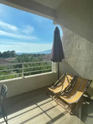 a patio with an umbrella and two chairs on a balcony at APPARTEMENT DUPLEX PORTICCIO Centre in Porticcio