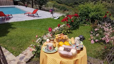a table with a plate of food on it next to a pool at Villa Capraghjese in Galeria