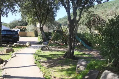 a swing set in a yard with trees and a sidewalk at Chez Pierre à Porto-Vecchio in Porto-Vecchio