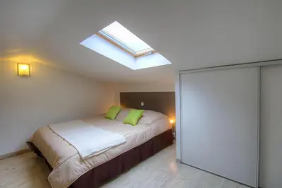 a bedroom with a bed with green pillows and a skylight at Chez Pierre à Porto-Vecchio in Porto-Vecchio